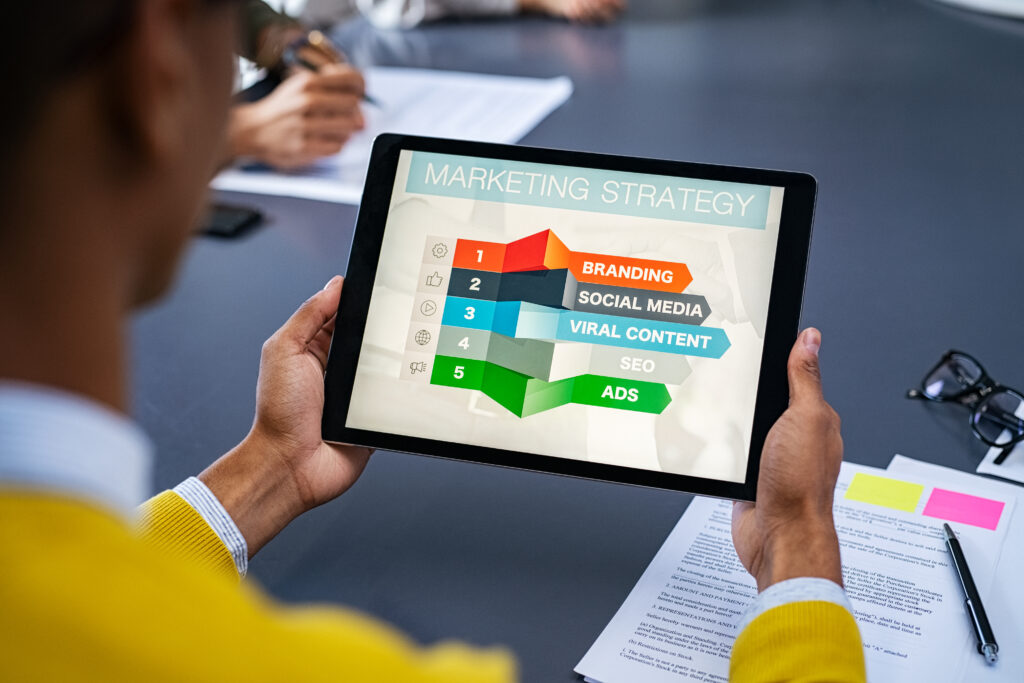 Digital Marketing Strategy on a tablet that mentions SEO, social media, ads, viral content and branding